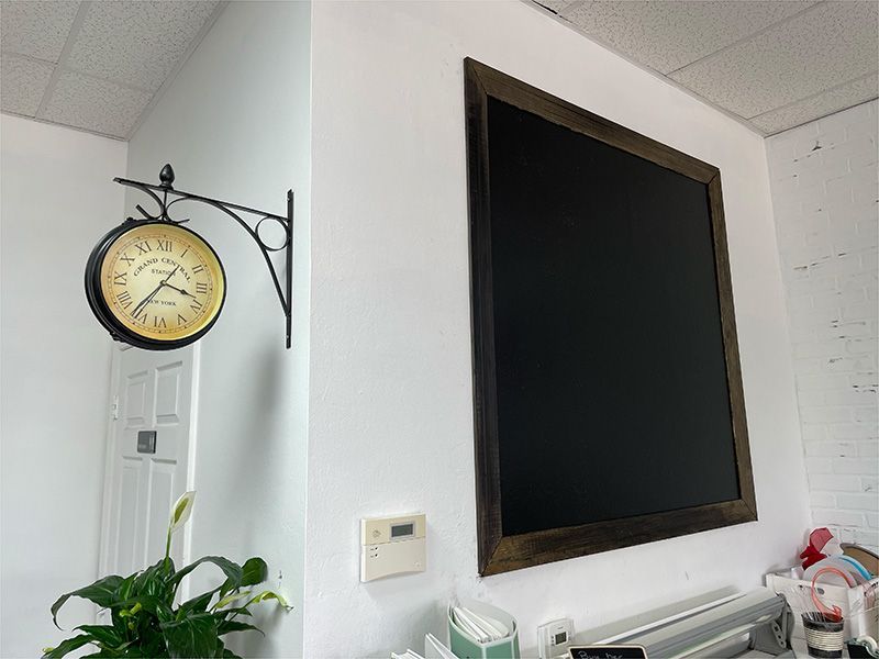 A clock is hanging on a wall next to a blackboard