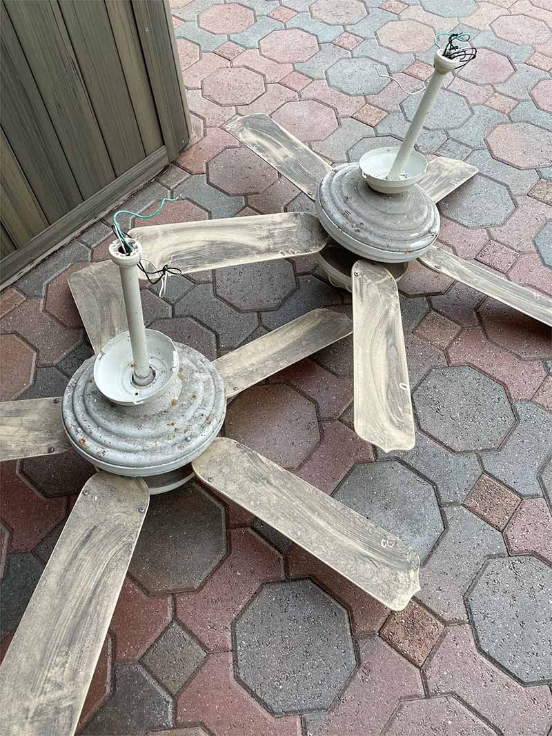 Two ceiling fans are sitting on top of a brick floor.