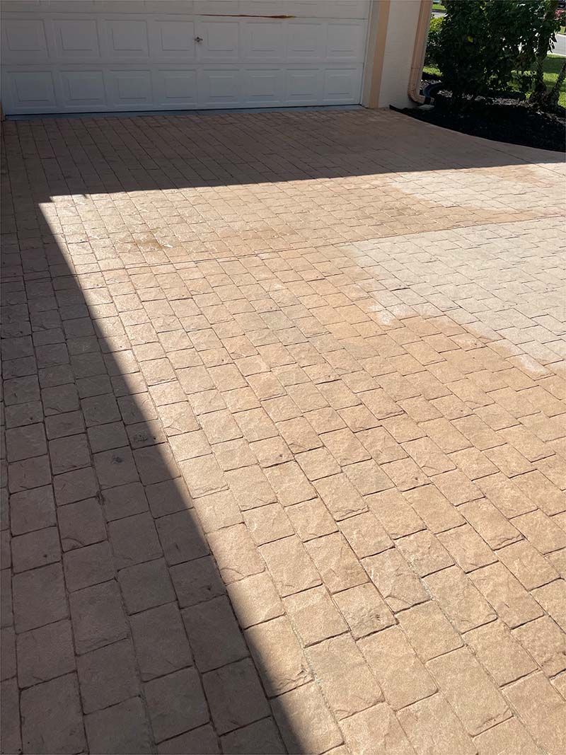 A brick driveway with a garage door in the background.