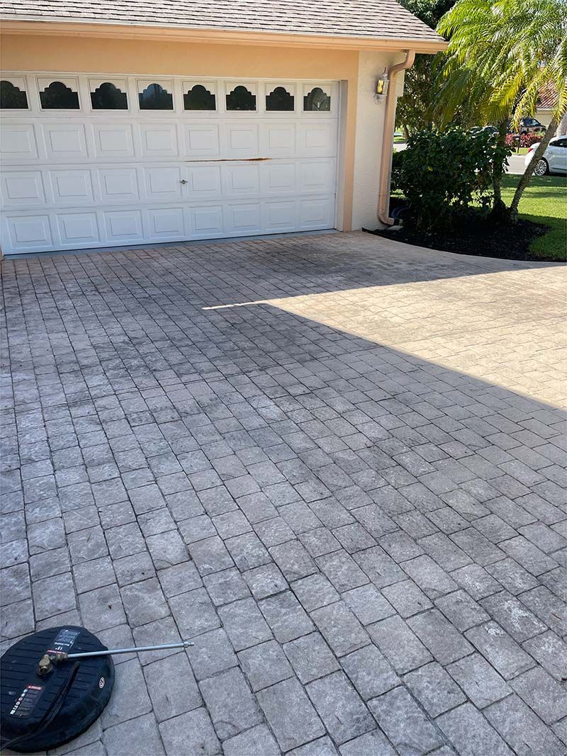 A brick driveway in front of a house with a white garage door.
