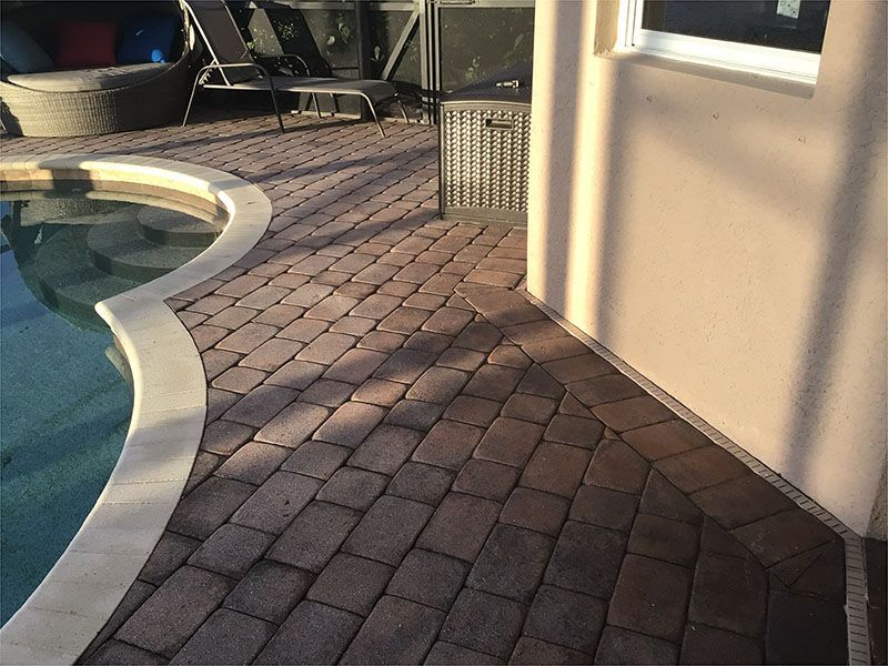 A man is using a high pressure washer to clean a sidewalk.