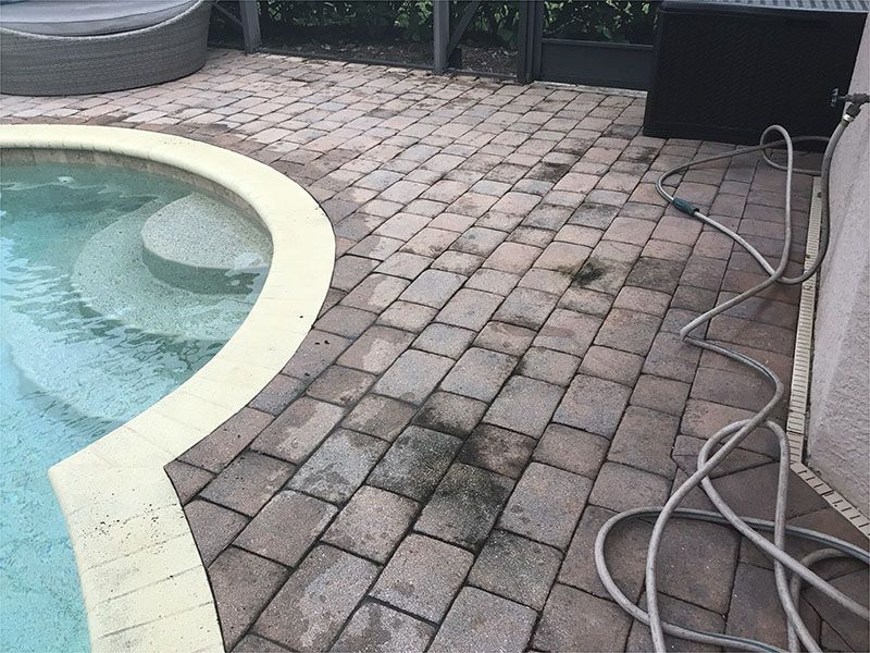 A brick patio with a swimming pool in the background.