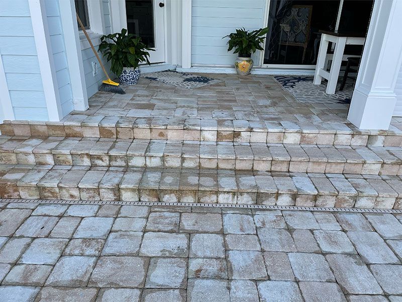 A brick walkway with stairs leading up to the front door of a house.