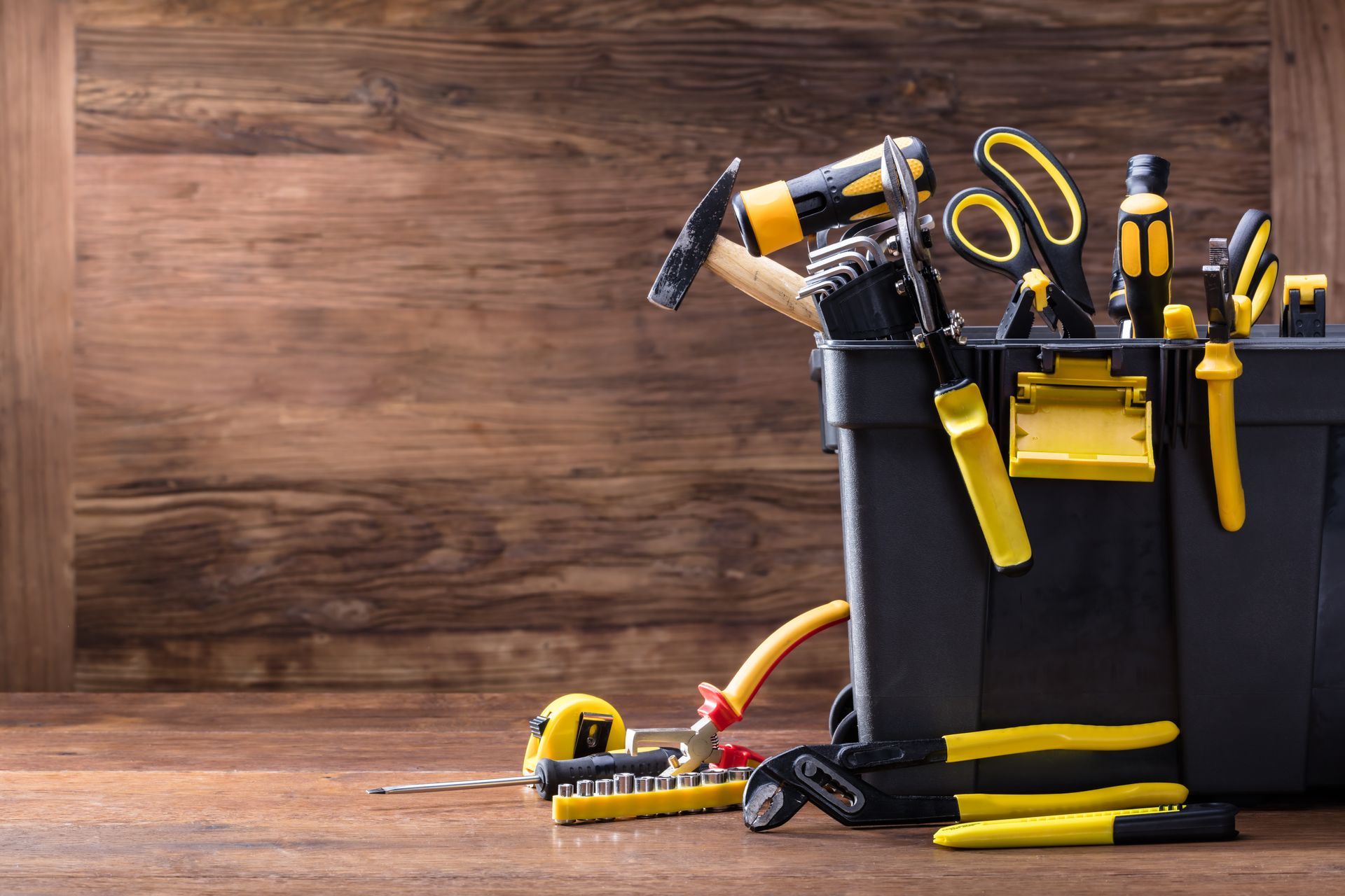 A toolbox filled with yellow and black tools on a wooden table.