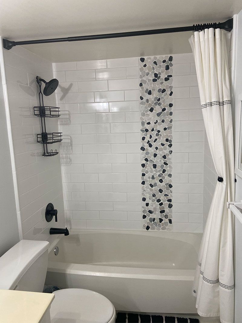 A bathroom with a toilet , tub , shower and shower curtain.