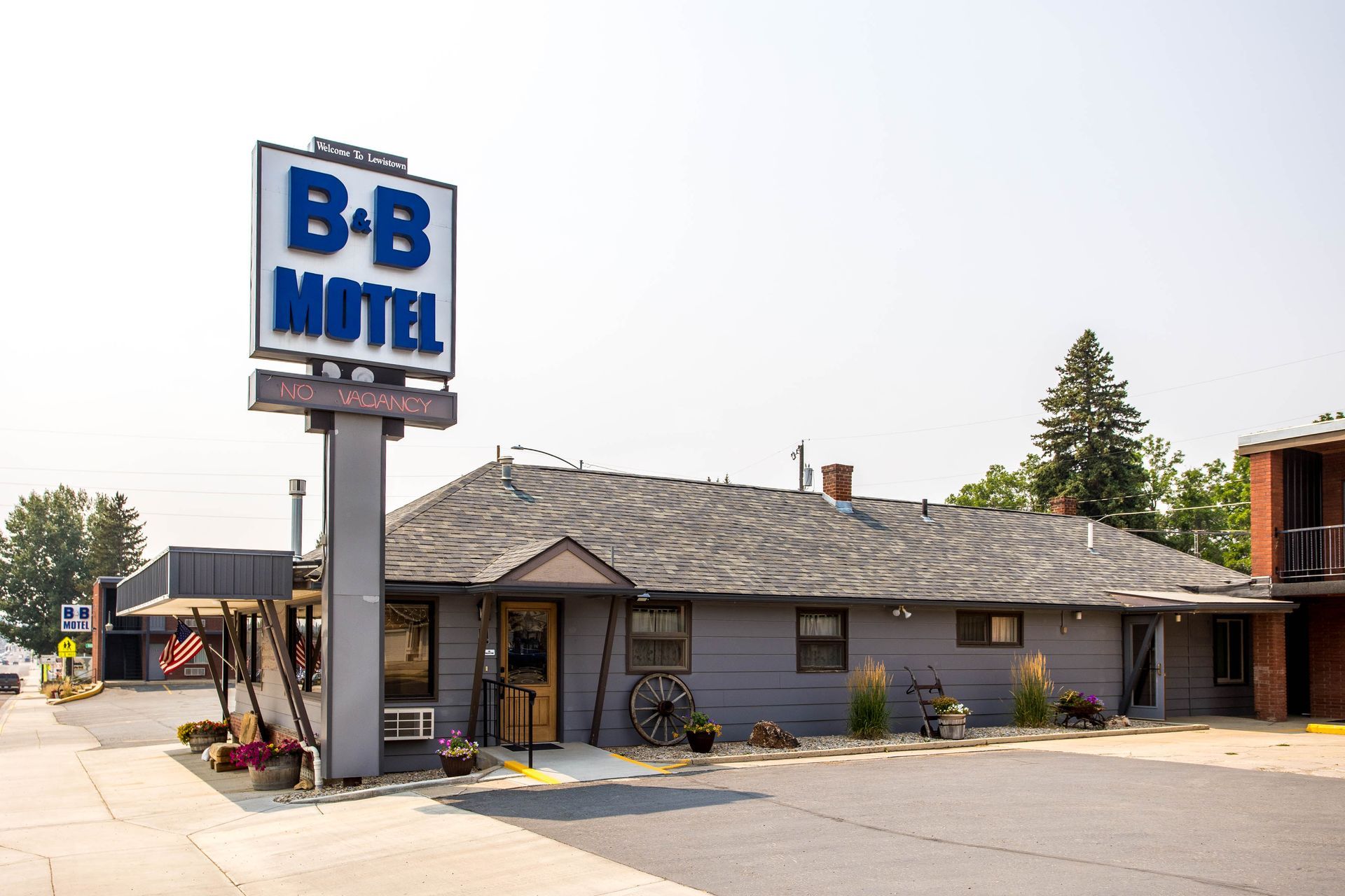 B+B Motel exterior with sign. Gray building with a parking lot and a tall sign.