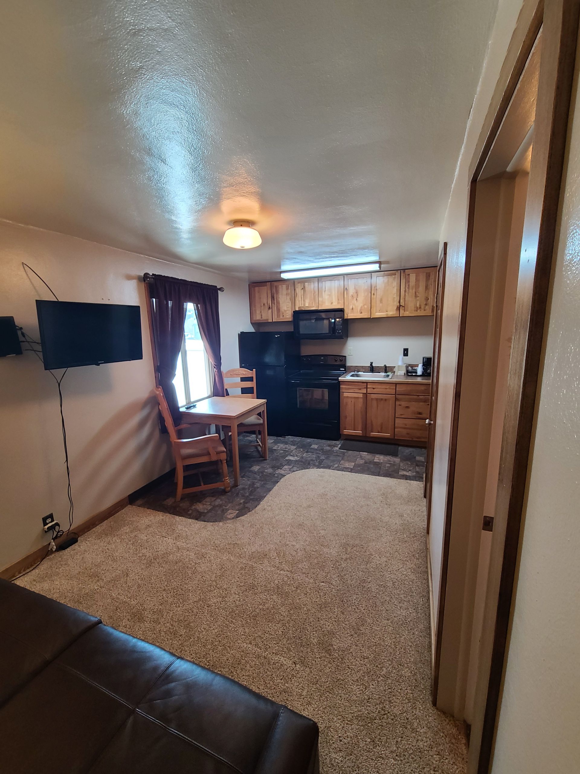 Cozy, carpeted interior with kitchen and dining area; a doorway leads to another room.