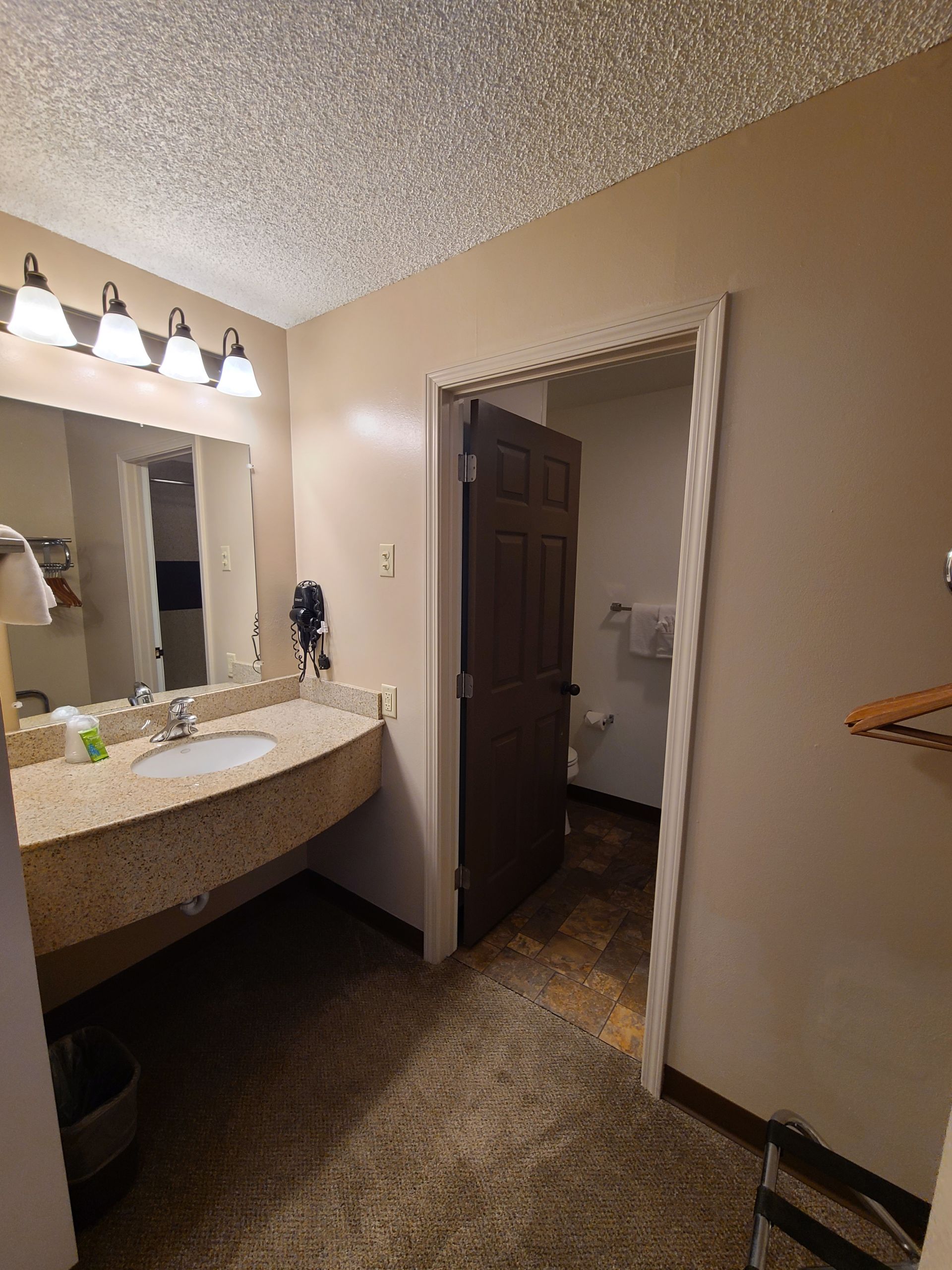 Bathroom with a vanity, mirror, and a doorway leading to a toilet room.