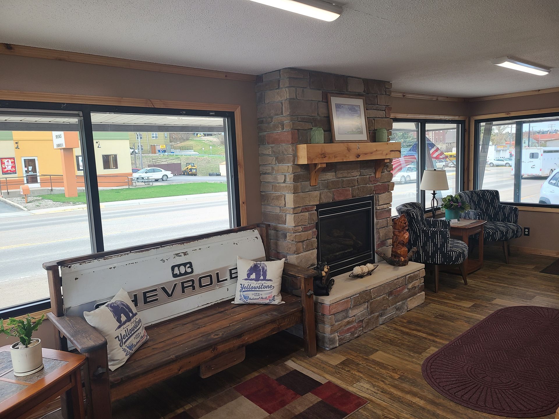 Cozy waiting area with stone fireplace, wooden bench, and large windows overlooking a street.