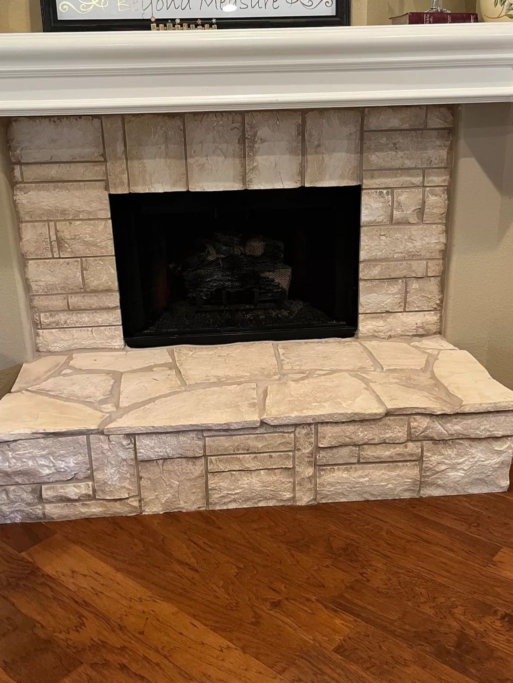 Stone fireplace with a black firebox and light tan hearth, set against a hardwood floor.