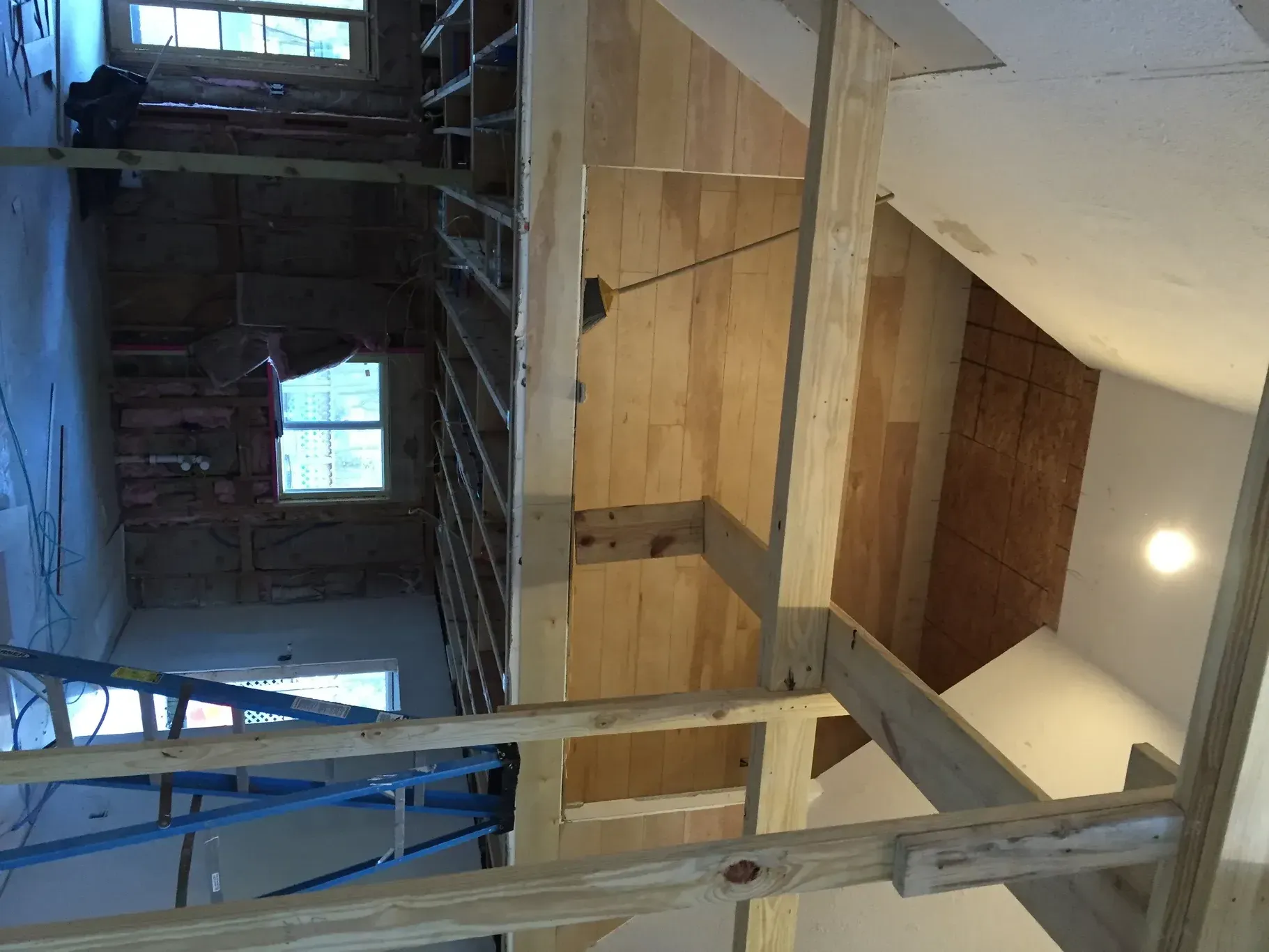 Interior construction site with scaffolding, exposed brick, wood panels, and a sloped ceiling