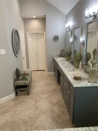 Modern bathroom vanity with double mirrors, marble countertop, and beige tiled floor.