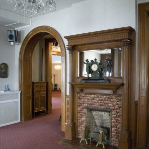 Interior room with ornate archway, carved mantel fireplace, and red carpeted floor