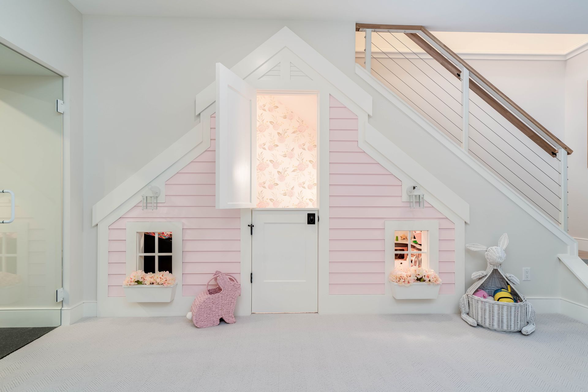 Pink dollhouse playroom with a white door, windows, and built-in staircase seating