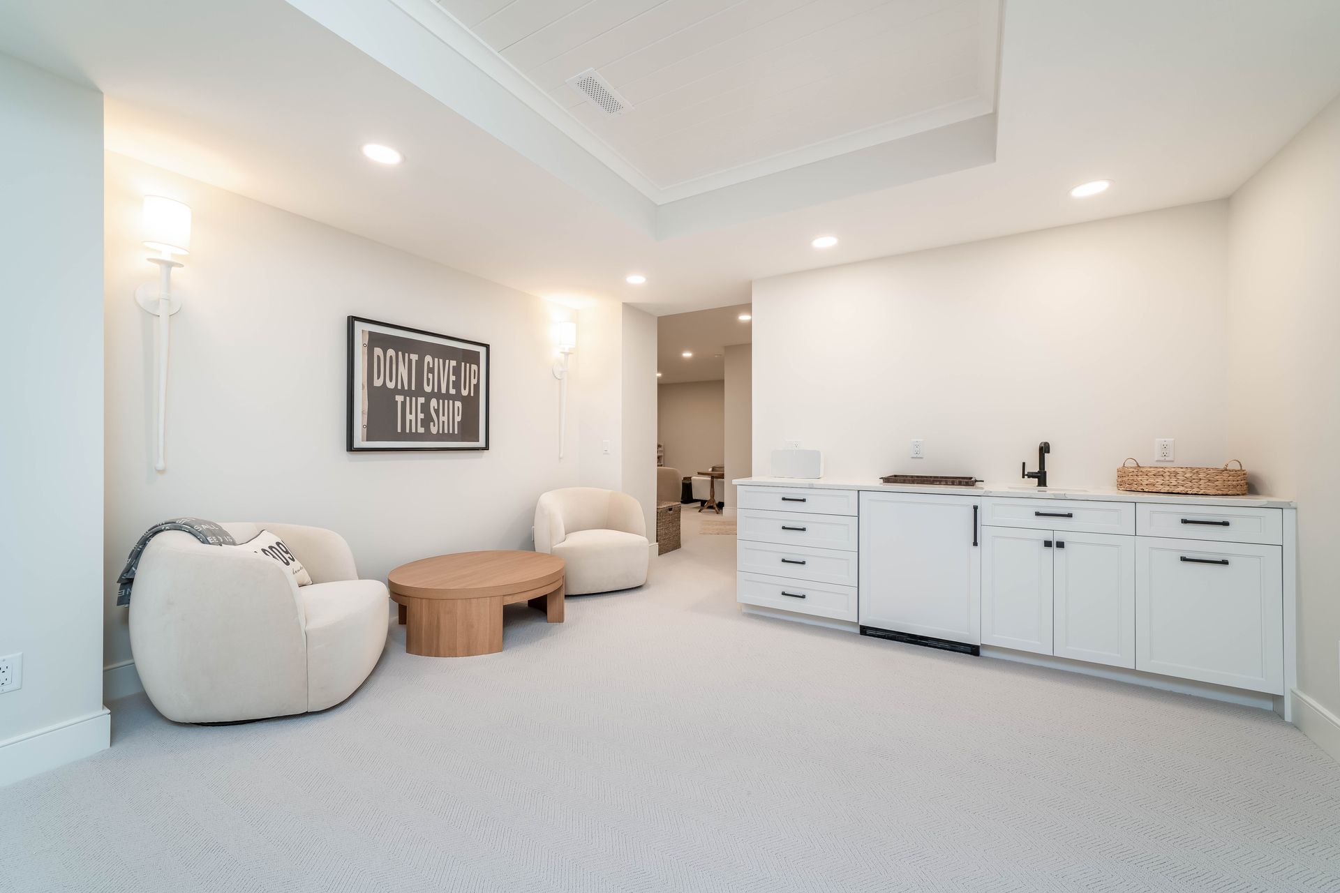 A living room with two chairs , a table , and a sink.