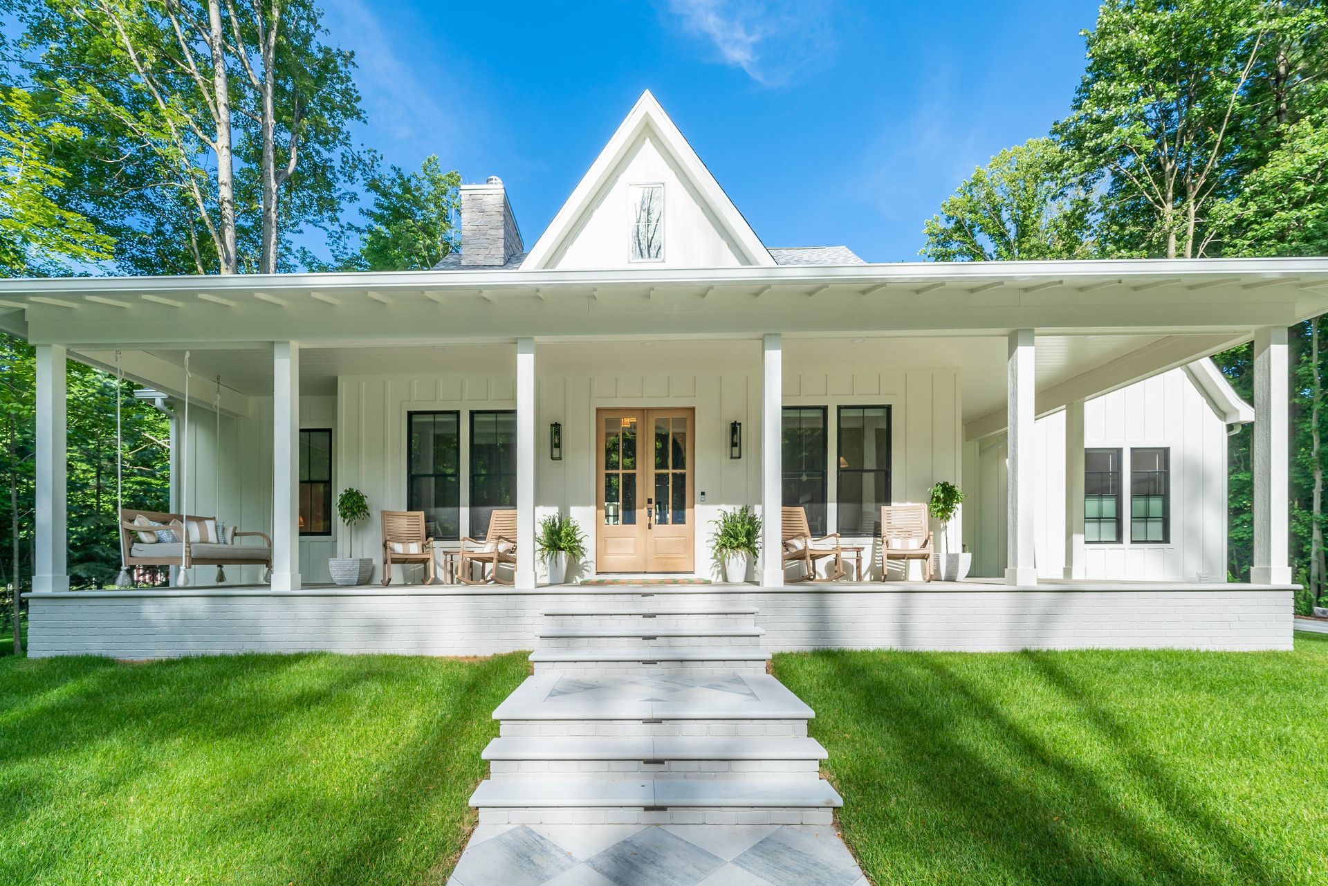 A white house with a large porch and steps leading to it.