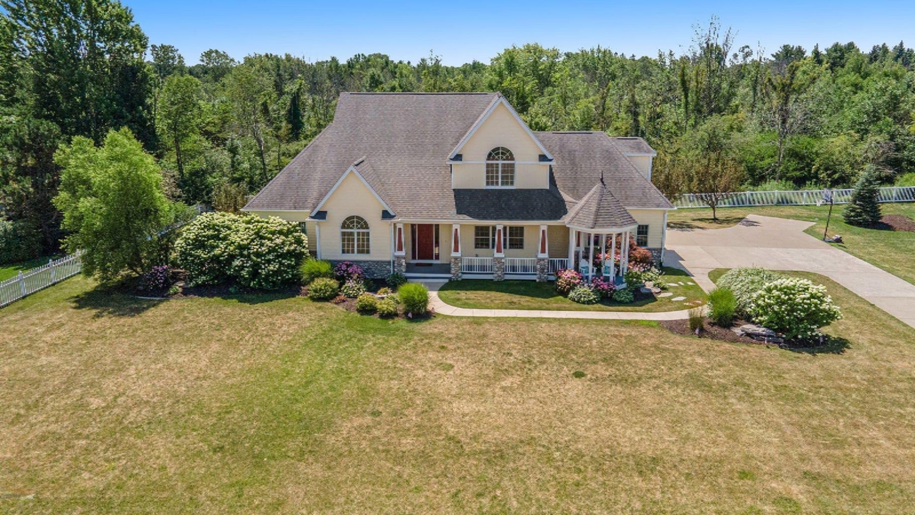 An aerial view of a large white house surrounded by trees and grass.