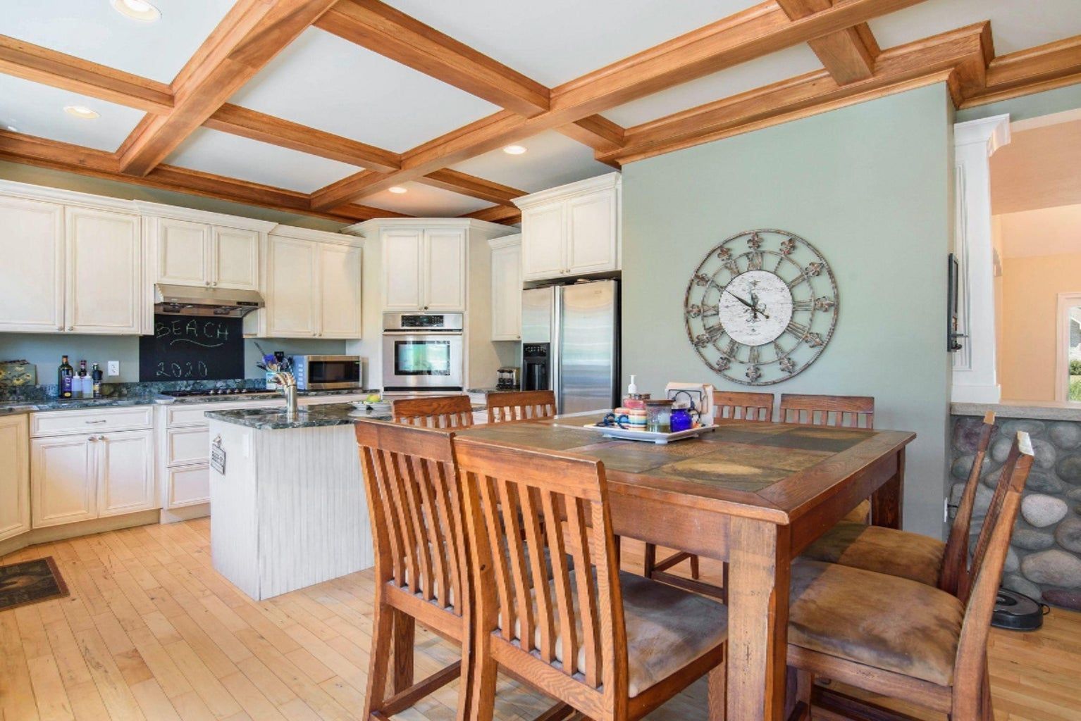 A kitchen with a wooden table and chairs and a clock on the wall.