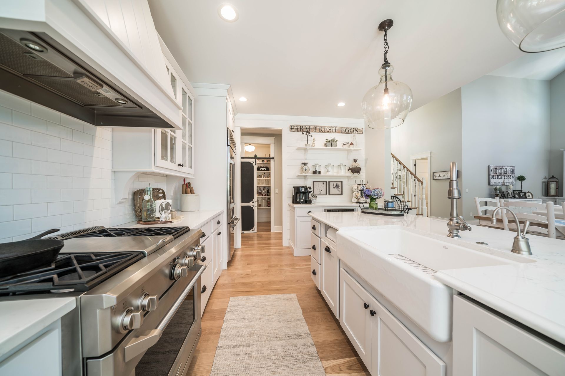 A kitchen with white cabinets , stainless steel appliances , a sink and a stove.
