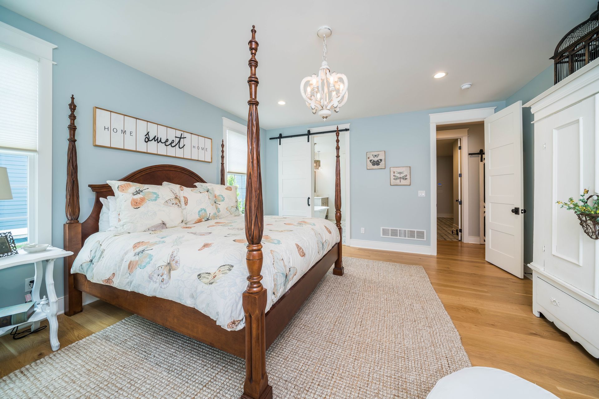 A bedroom with a four poster bed and a chandelier.