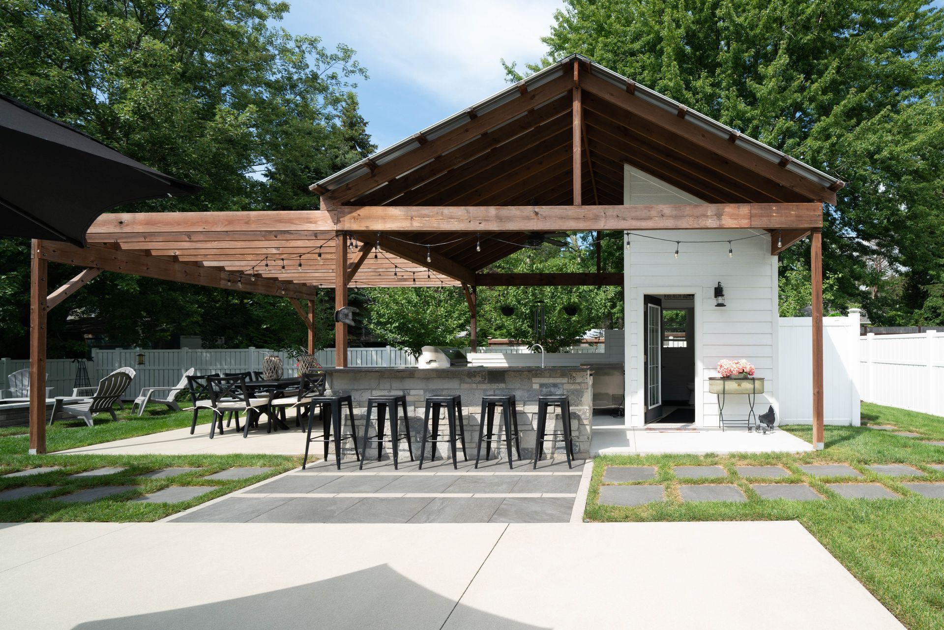 A large white building with a wooden roof is sitting in the middle of a backyard.