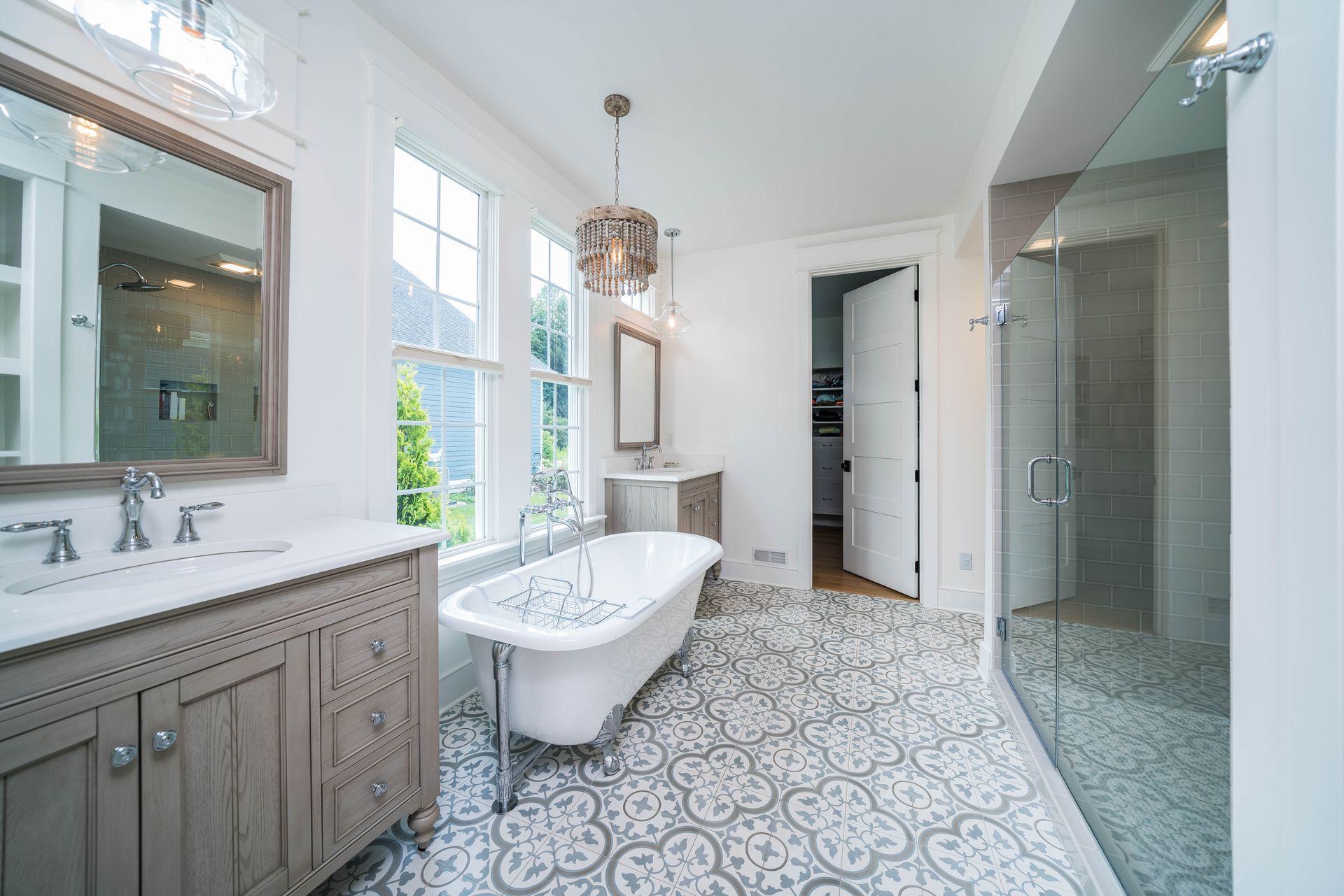 Bright modern bathroom with patterned tile, freestanding tub, double vanity, and glass shower en suite