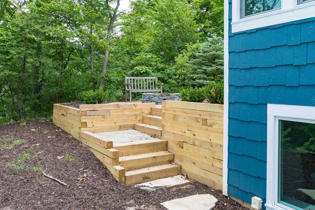 A blue house with a wooden deck and stairs in front of it.