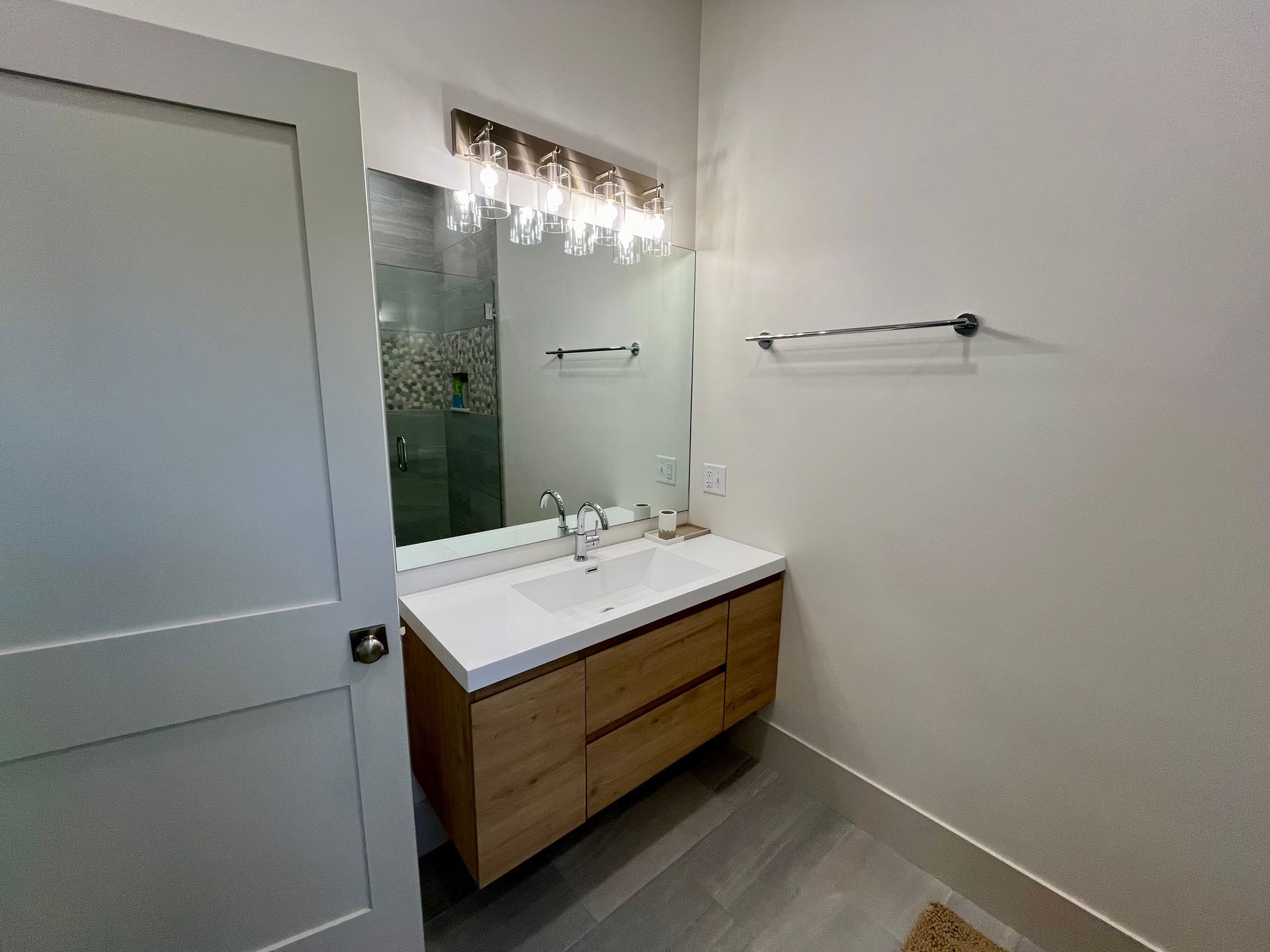 A bathroom with a sink , mirror and towel rack.
