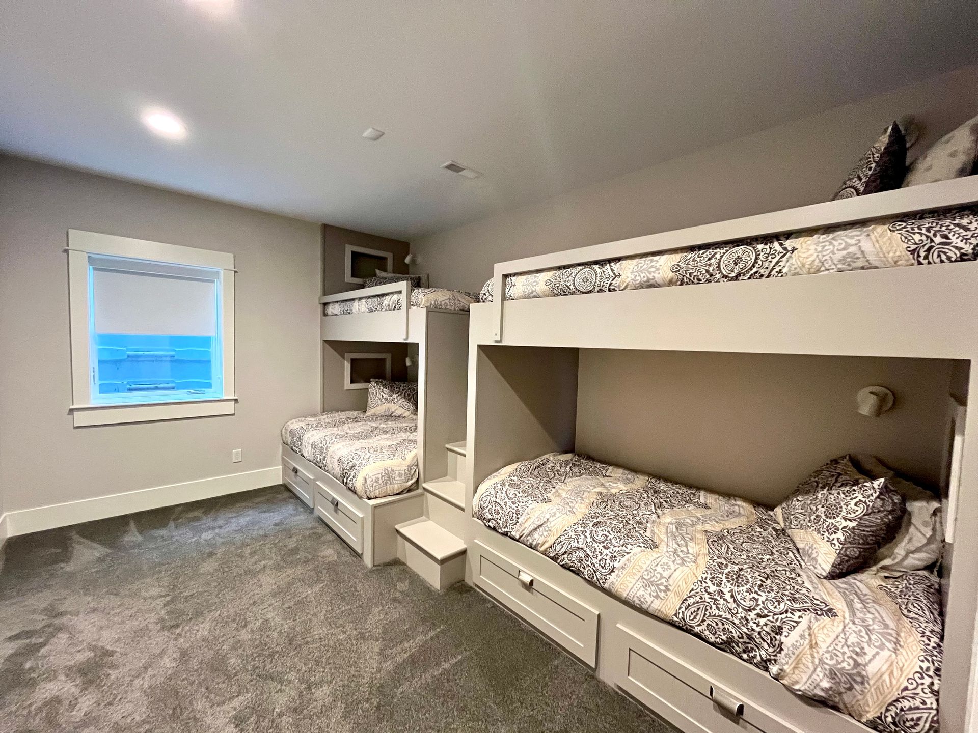 A bedroom with three bunk beds and a window.