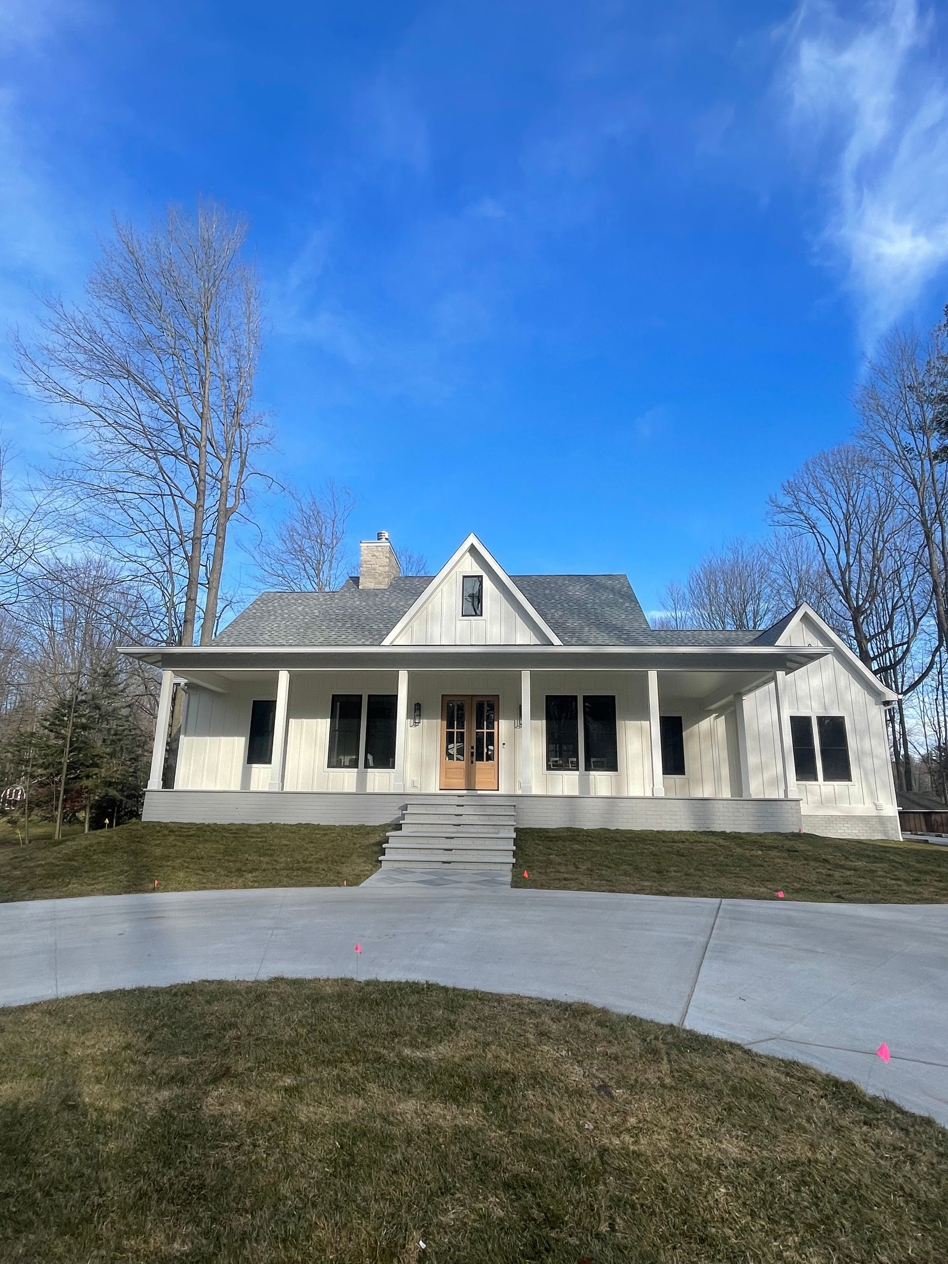 A white house with a porch and a blue sky in the background.
