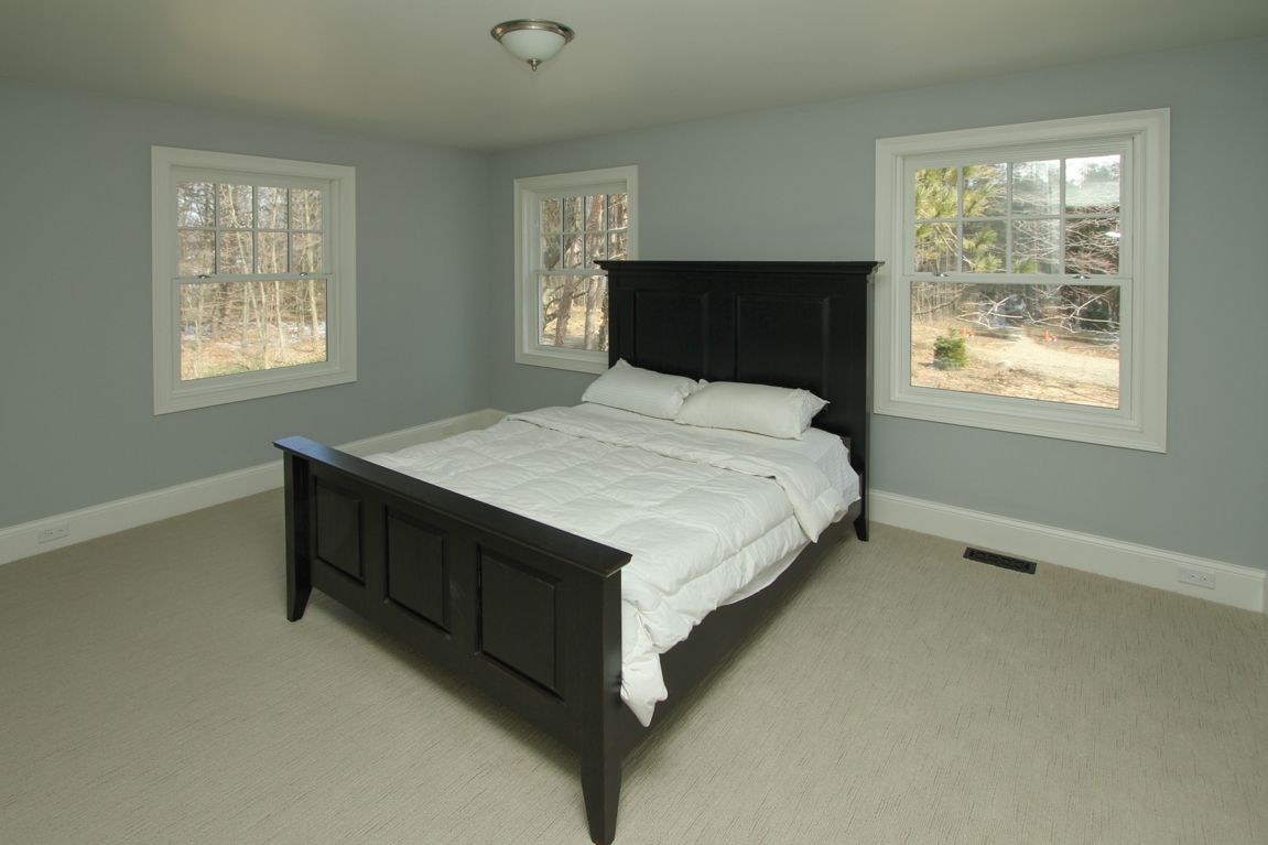 A bedroom with a black bed and two windows