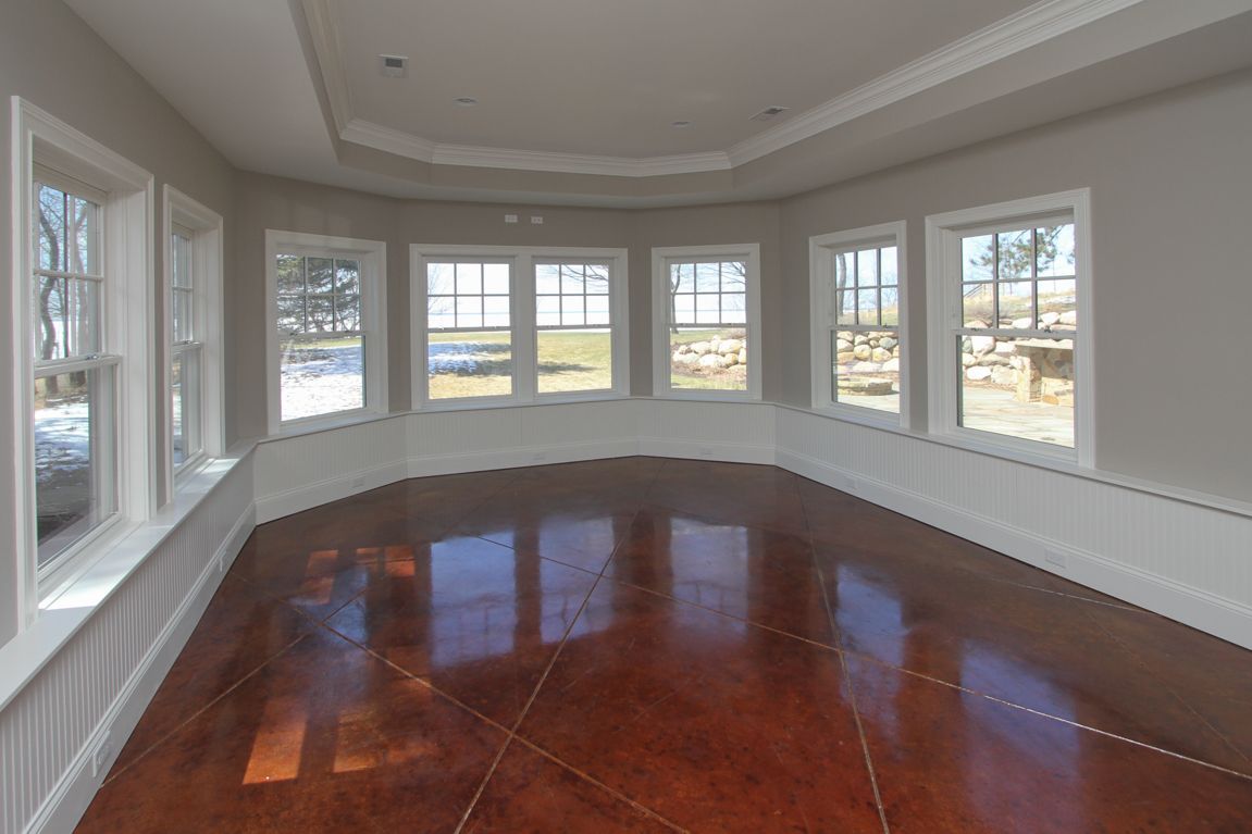 An empty room with a wooden floor and lots of windows