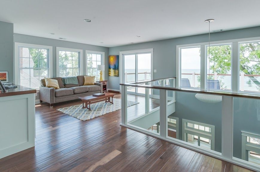 A living room with a couch , coffee table , and lots of windows.