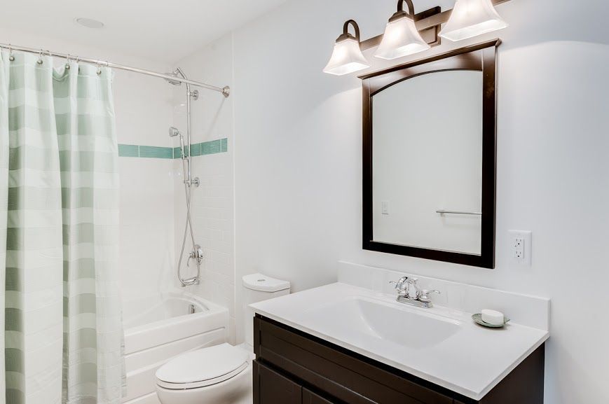 A bathroom with a sink , toilet , shower and mirror.