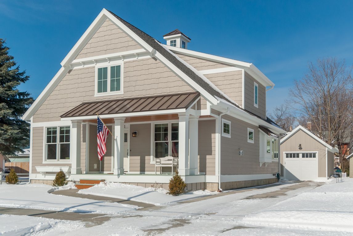 A house with snow on the ground and a flag on the porch
