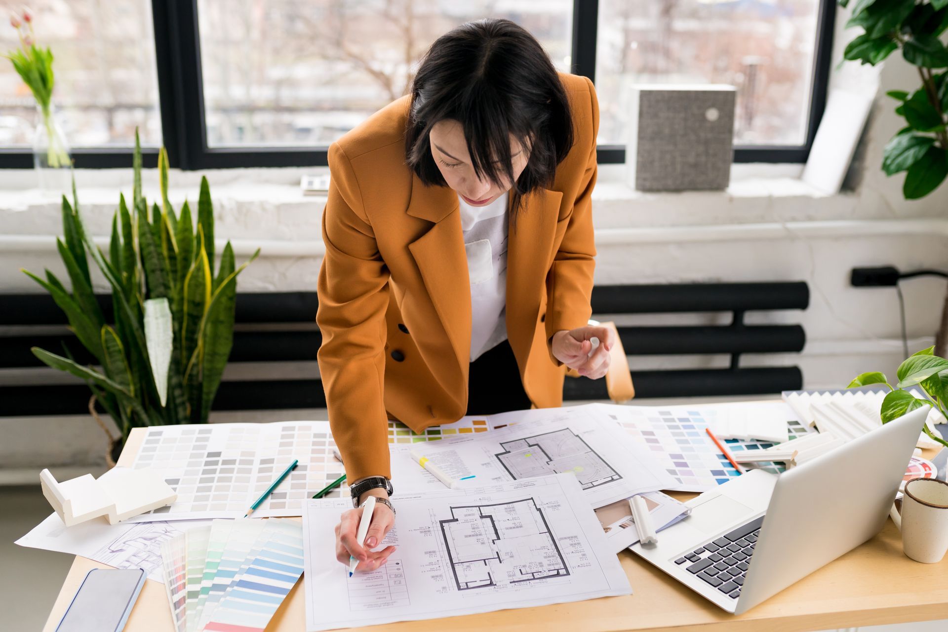 A woman is sitting at a desk looking at a blueprint.