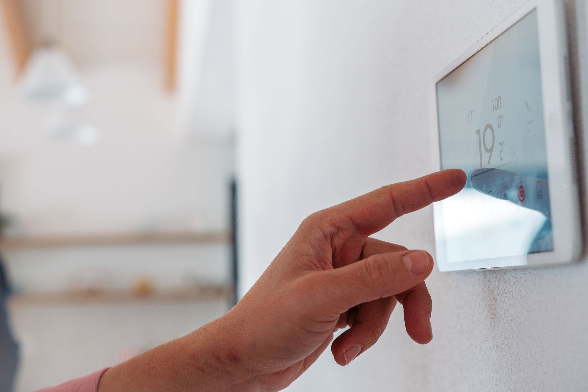 A person is pressing a button on a thermostat.