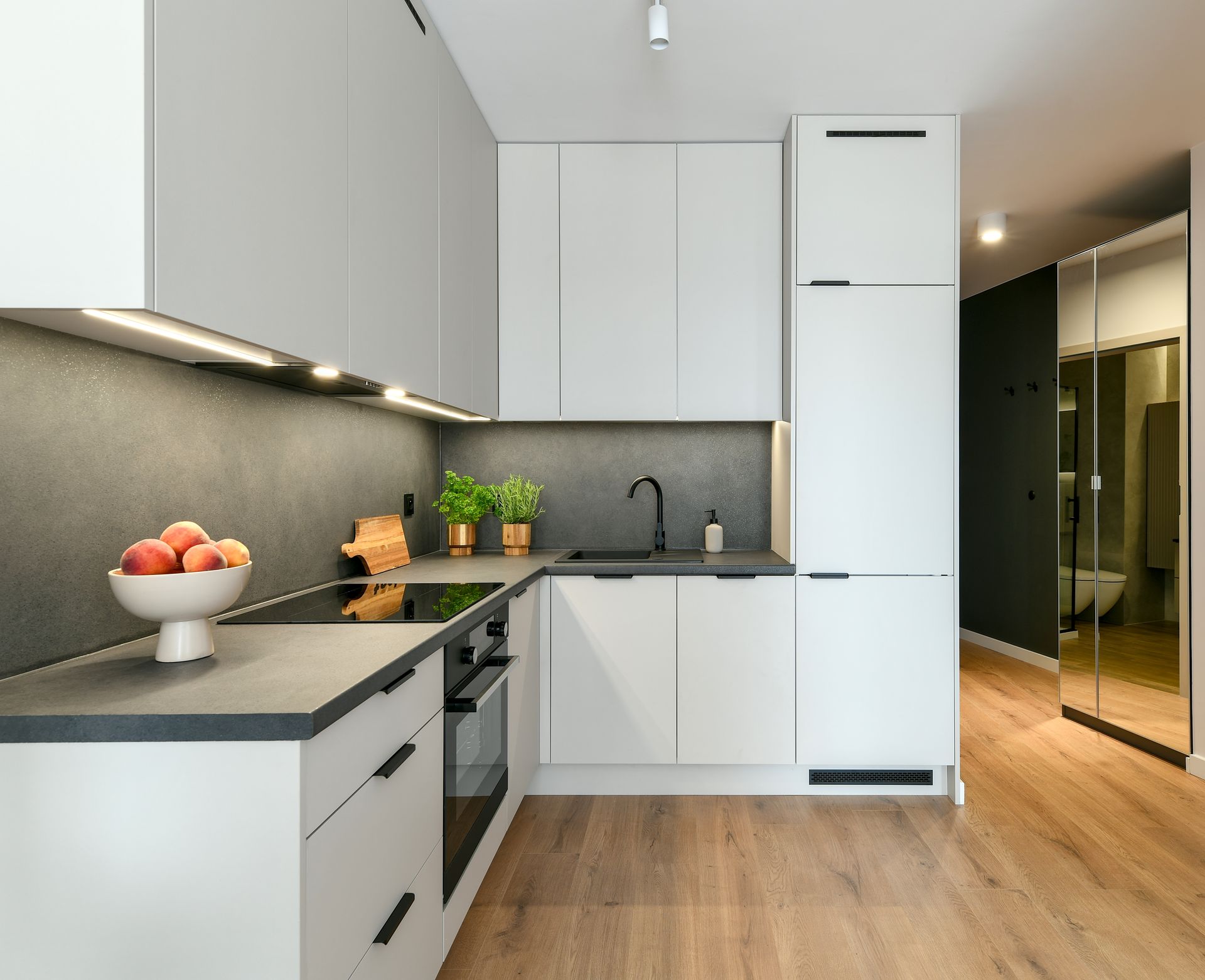 A kitchen with white cabinets and a bowl of fruit on the counter.