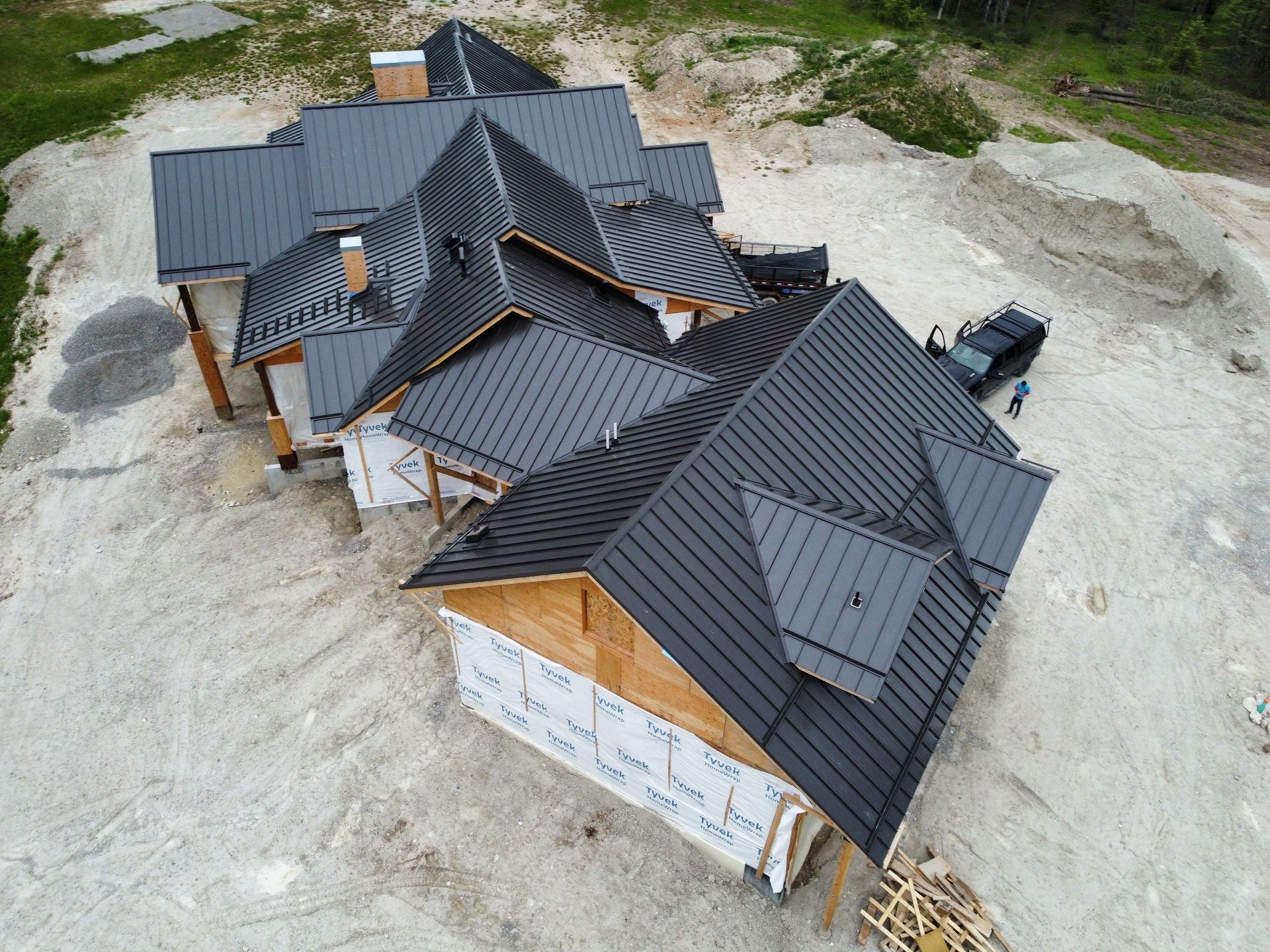 Drone view of a house with a black metal roof under construction.