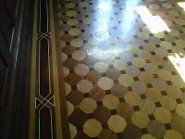 Polished patterned floor with light reflecting; a dark wooden border on the left.