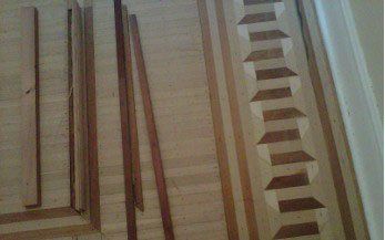 Wood floor under construction with a decorative staircase design. Various wood planks are scattered around.