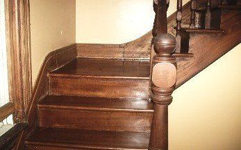 Wooden staircase with dark stained steps and balustrade, inside a building.