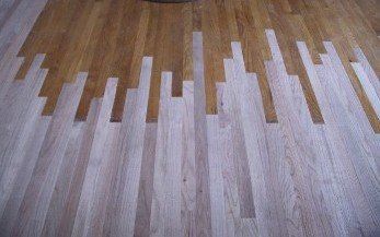 Wooden floor with an abstract two-tone design: light and dark wood, vertical lines create a cityscape-like pattern.