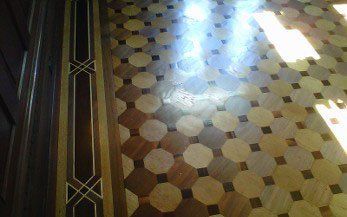 Wooden floor with octagonal tiles in various wood tones. A decorative border runs along the side.