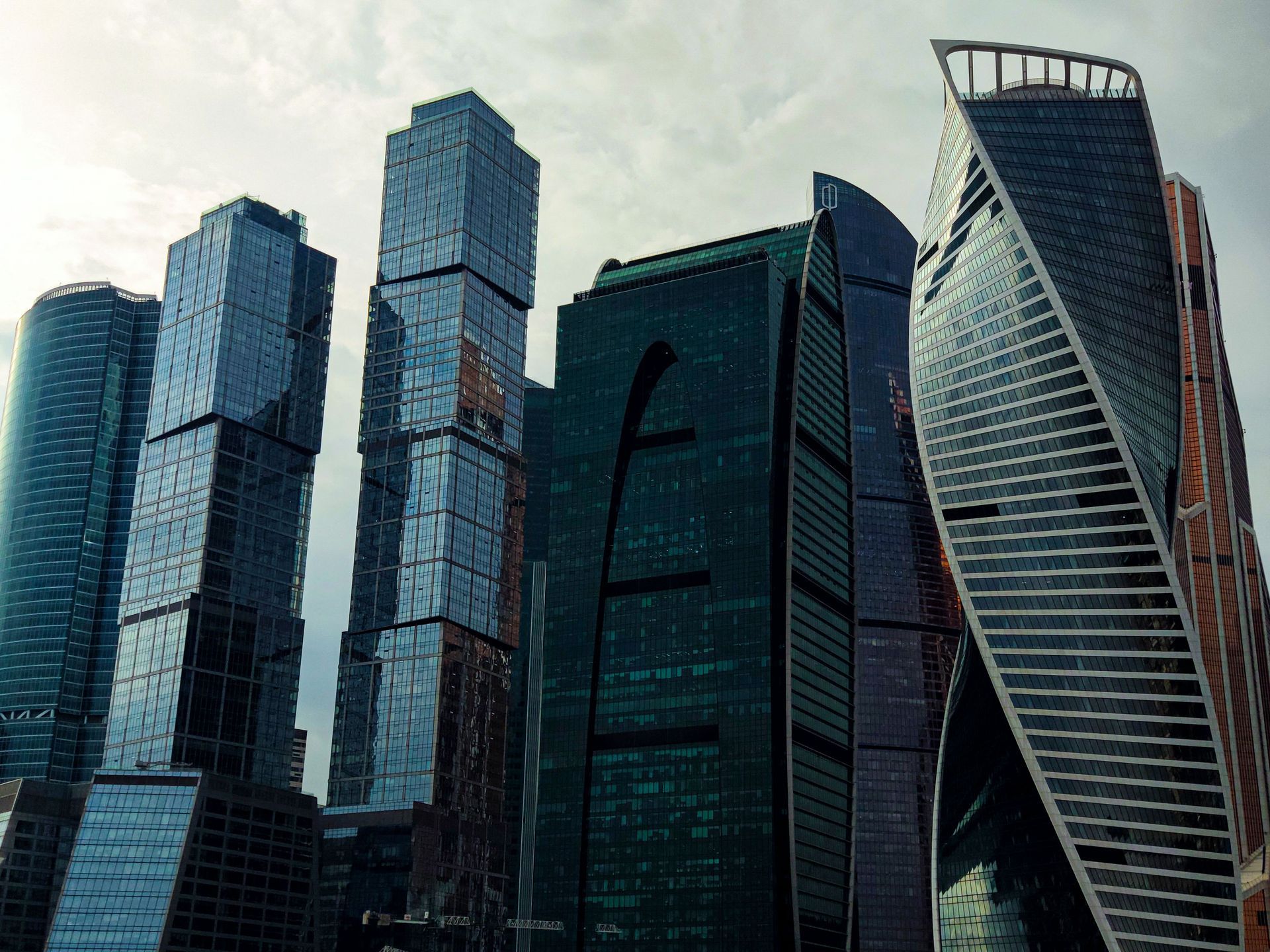 Modern glass skyscrapers, including a twisting tower, against a clear sky