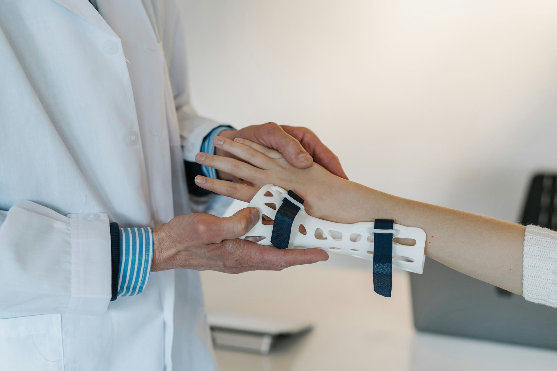 A doctor is holding a child 's hand with a cast on it.