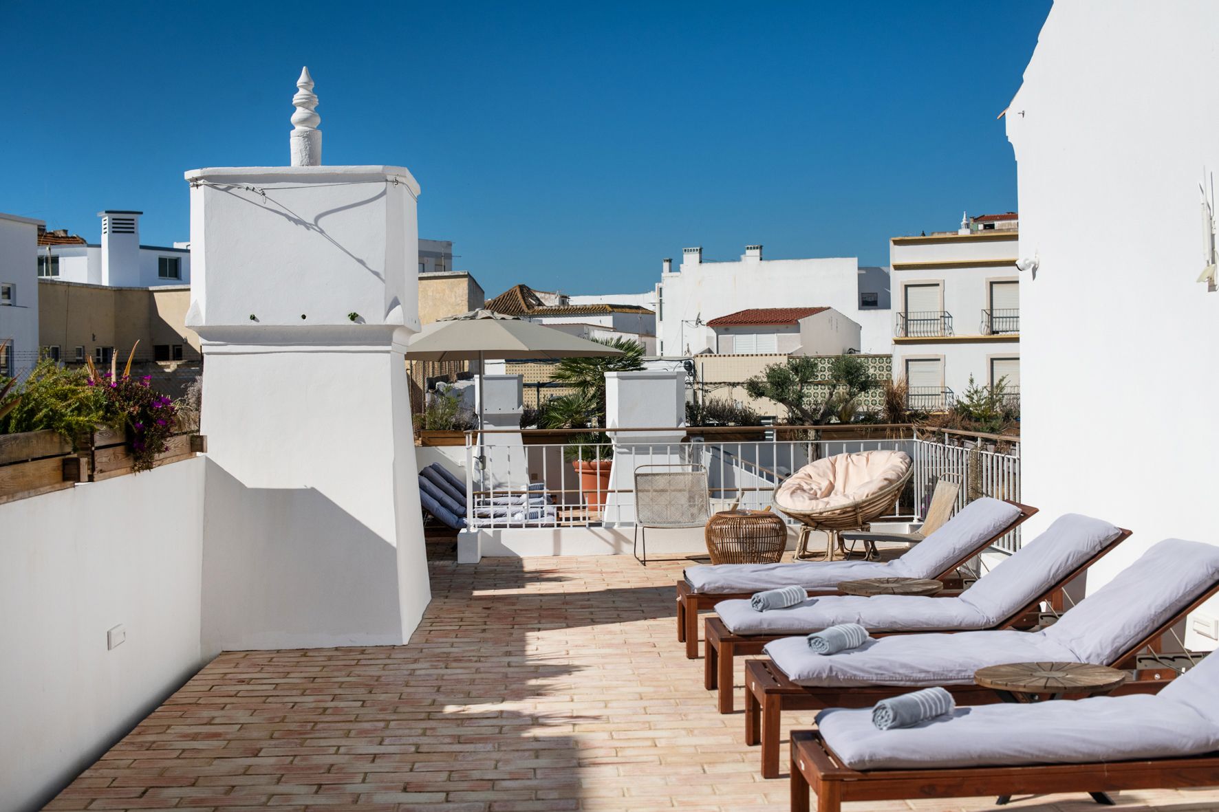 a row of lounge chairs are lined up on a rooftop terrace .