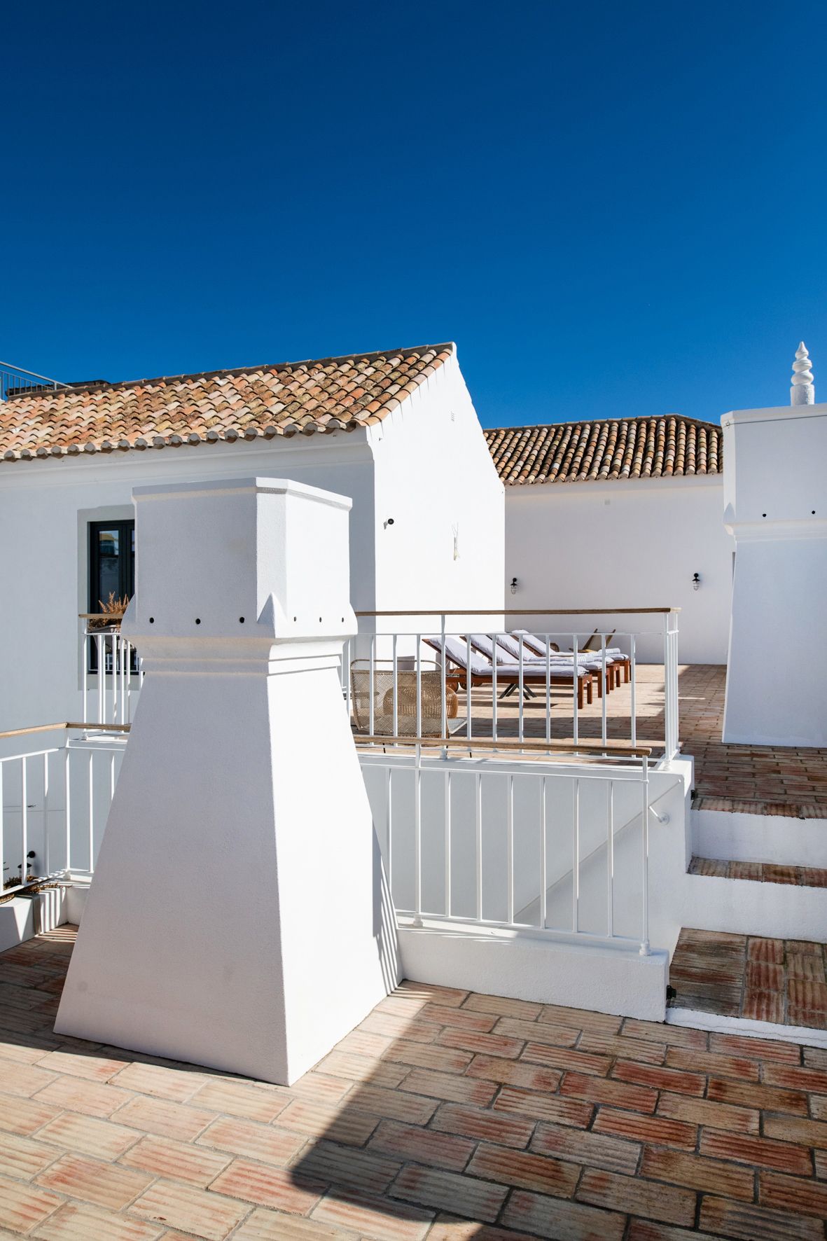 a white building with a balcony and chairs on it .
