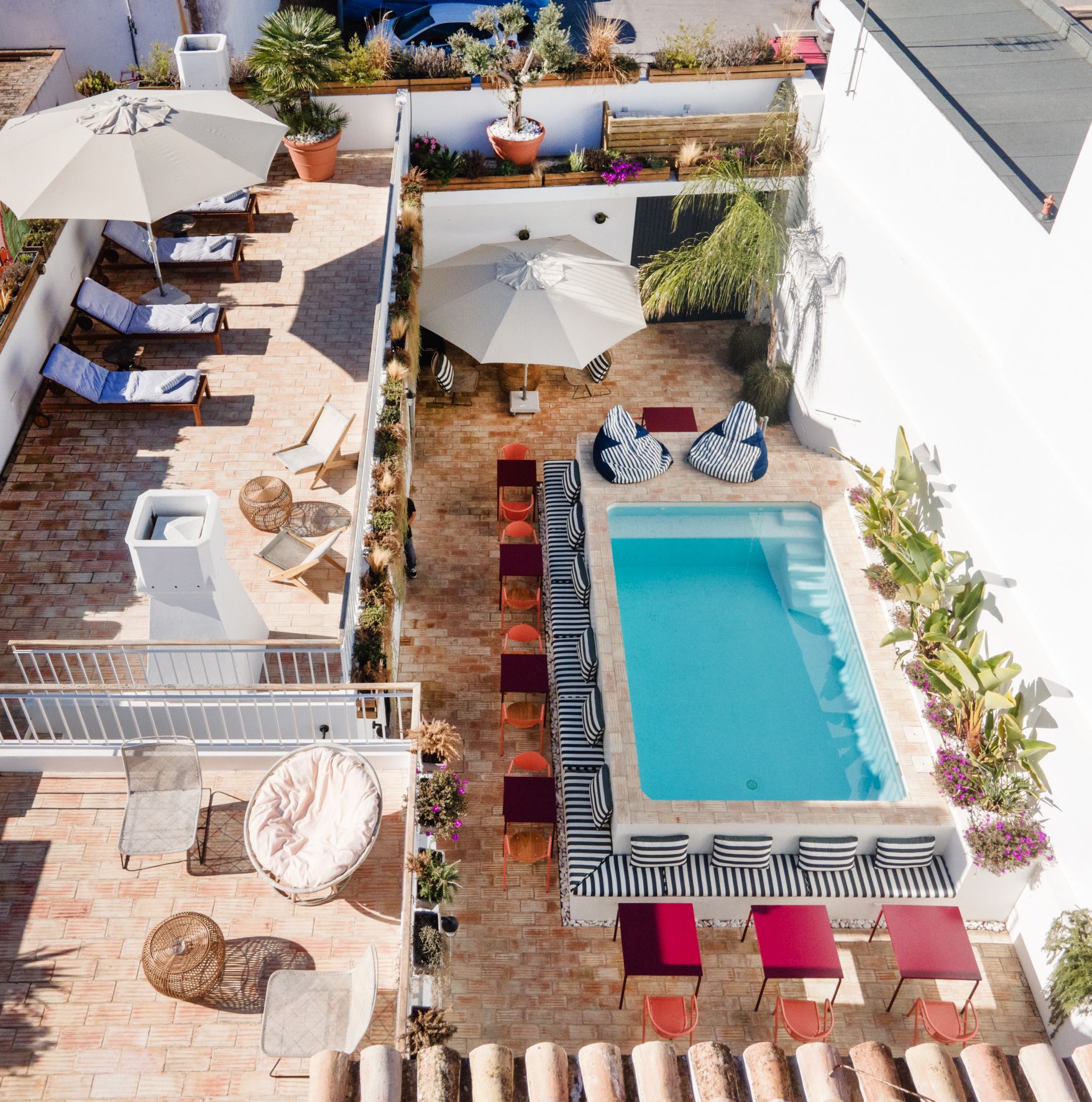 an aerial view of a swimming pool surrounded by chairs and umbrellas
