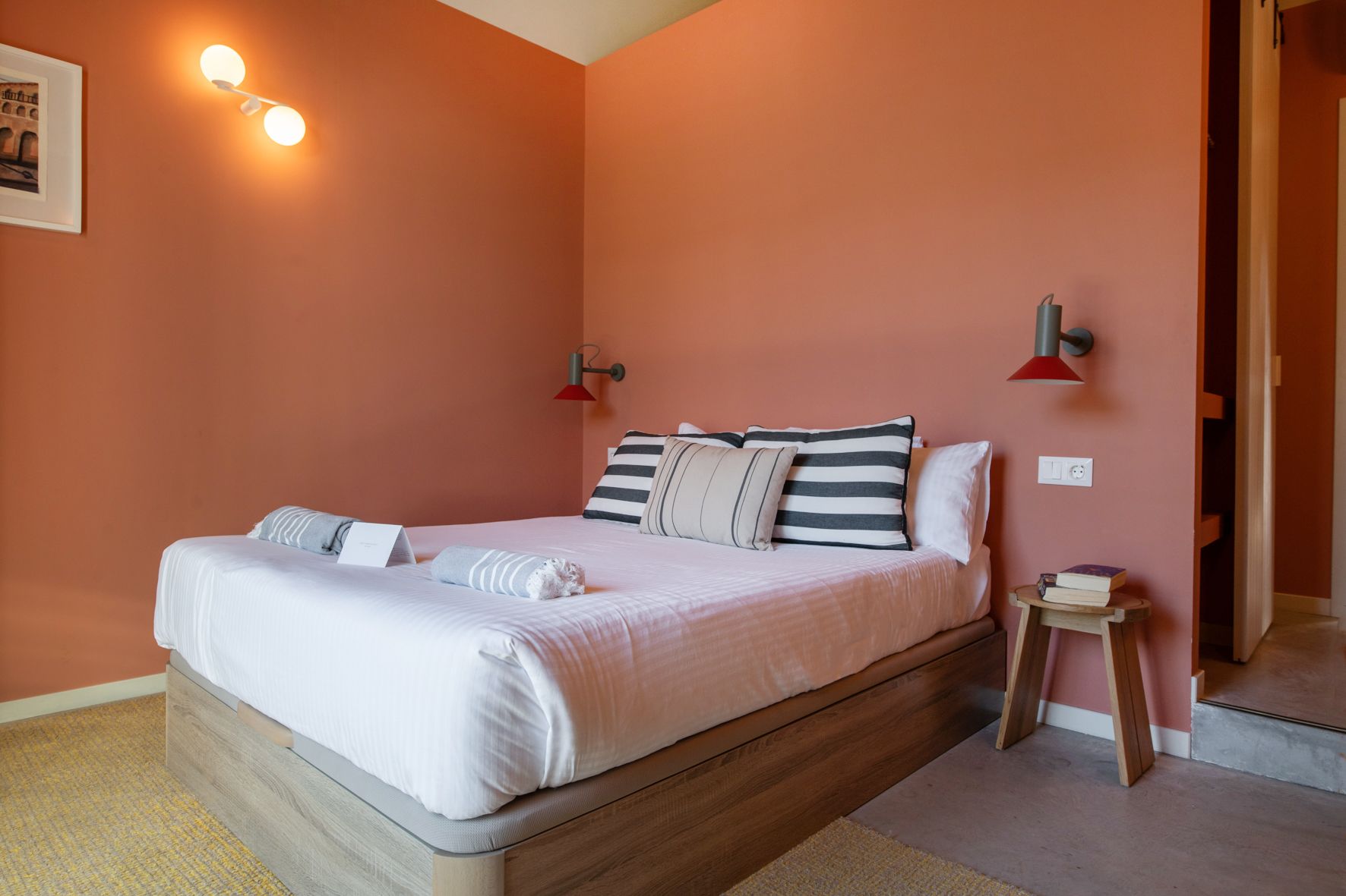 A bedroom with a bed , nightstand , and pink walls.